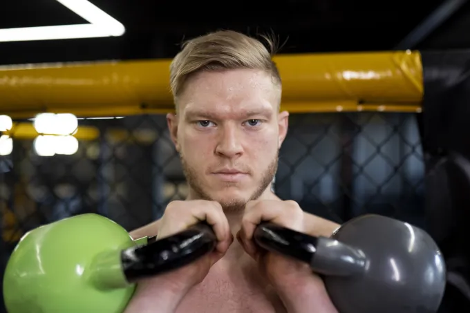 A fighter training with kettlebells to improve his strength for martial arts