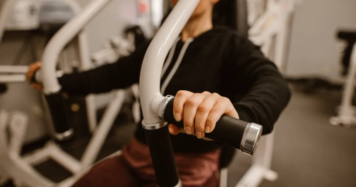 Lifter performing a controlled seated chest press machine repetition in a bright gym