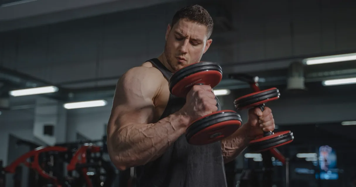 Focused lifter performing a controlled dumbbell curl close to muscular failure