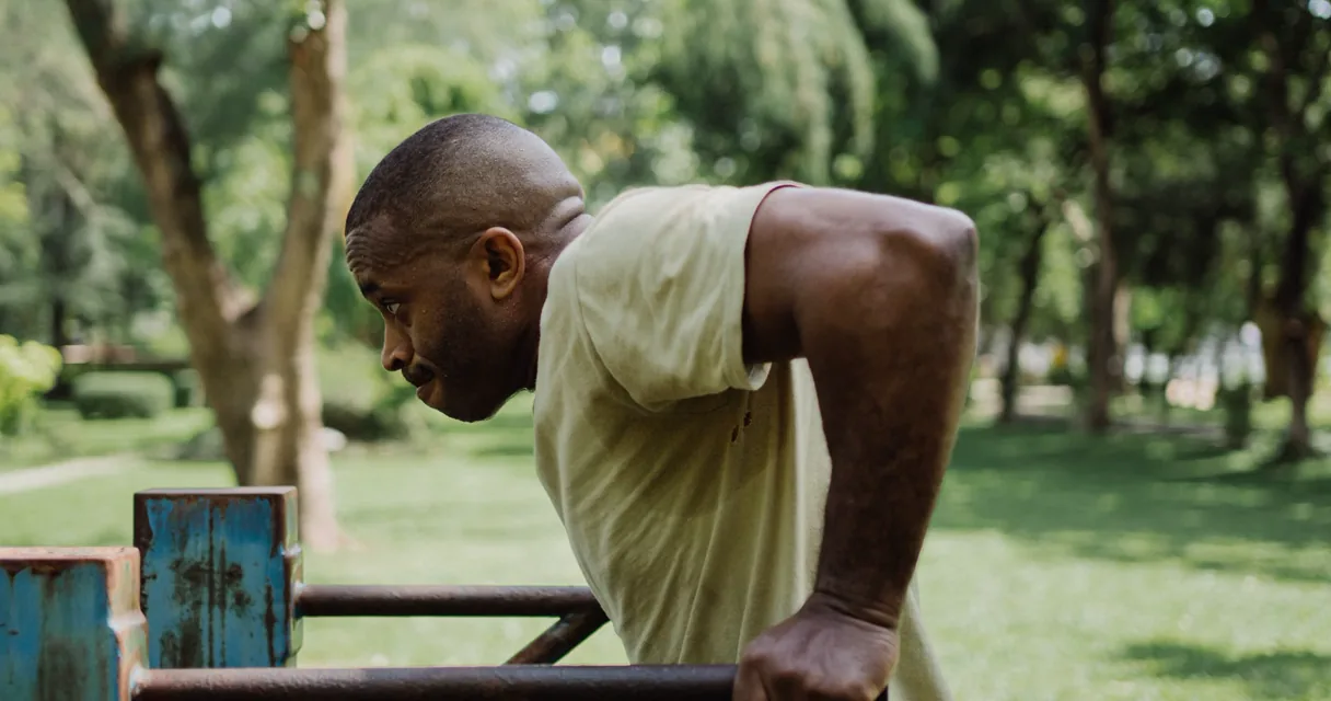 Athlete performing a controlled weighted dip on parallel bars in a gym